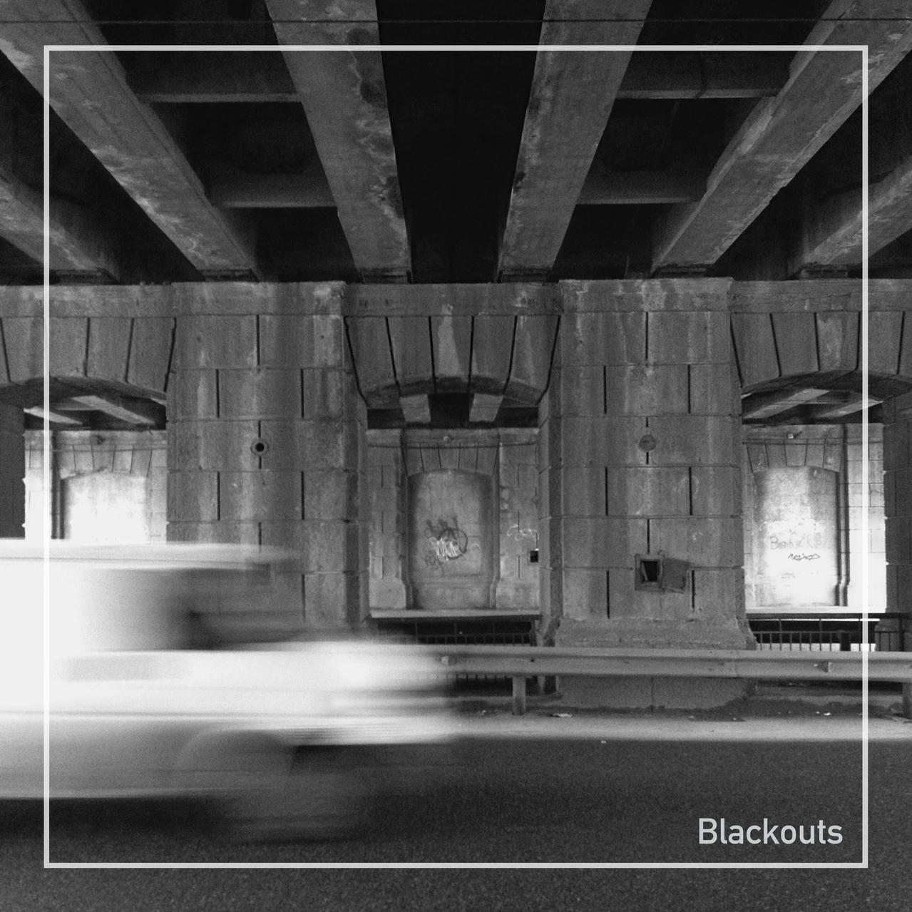 black and white photo of a bridge-like structure with a blurred white van passing by in the foreground